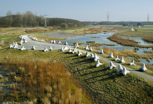 <i>Wellenbrecher (Wave Breaker)</i>,
2016<br />
Installation in public space, Emscherkunst Triennial, 2016,
60 concrete tetrapods (2,20 × 2,20 × 2,20 m each, 6 tonnes) all over installation 130 × 20 m<br />
The installation 'Wave-Breaker' metaphorically recreates the imprint of Noah’s Ark on the grounds of the detention basin. The imprint was apparently discovered by a pilot near Turkey’s Mount Ararat in 1960. To create the monumental and segmented sculpture, the artist uses 60 wave-breaker (breakwaters) in the form of concrete tetrapod blocks, each measuring over two metres. These are used in the hydraulic engineering industry to protect coasts and banks and are usually found in coastal areas. Thus, she makes direct reference to the place and its protective function: After its completion, the detention basin will be utilized for absorbing flood waves in the case of heavy rainfall. The Wave-Breaker refer to both Noah’s Ark and the hope of a new beginning after a catastrophe caused by either climate change as well as how these are ingrained in the memory of humankind and are still being discussed today in the context of the plight of refugees. The question arises of who are the chosen ones, who are allowed to enter the boat? Wave-Breaker also symbolically stands for the breaking of political trends/ waves, most of all nationalist ideologies. (excerpt from a text by Lisa Maria Weber and Leonie Böhmer)